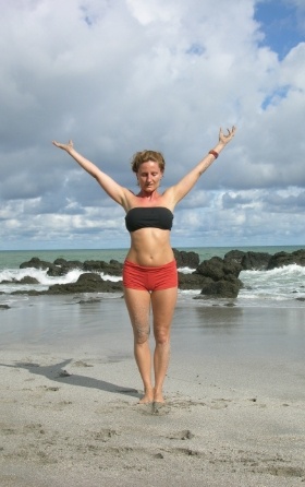 woman preforming yoga mountain pose on beach