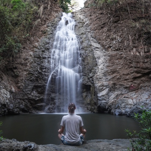 man meditating in-front of Montezuma Waterfall Costa Rica