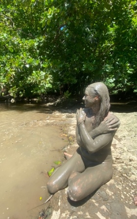 woman covered head to toe in mud bath